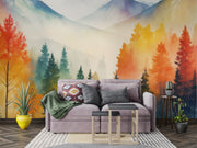 Watercolor mountain landscape wall mural with autumn forest in orange, yellow and teal, styled in modern living room.