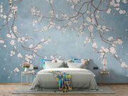 Cherry blossom wall mural with white flowers on twisting branches set against a rich blue background, creating a peaceful and stylish interior decor.