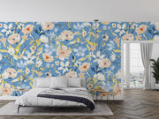 Bold botanical wall mural with vibrant blue, beige, and yellow flowers, styled in a modern bedroom.