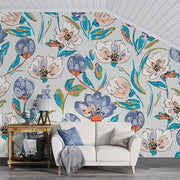 Modern artistic floral wall mural with bold blue, coral, and green flowers, styled in a bright living space with light wood furniture.