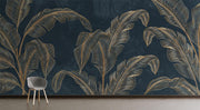 Golden banana leaf wall mural with metallic leaves on a deep black background.