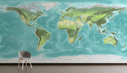 High-detail oversized world map wall mural showing terrain relief and ocean depths in turquoise and green, styled with modern furniture.