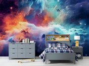Celestial Dreams galaxy wall mural with colorful nebula clouds in orange, blue, and purple tones, styled in a modern bedroom.