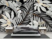 Black and white tropical leaf wall mural with gold accents, featuring monstera and palm leaves in a modern botanical design.