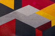 Modern geometric wall mural with an urban brick texture featuring bold abstract shapes in red, yellow, black, and gray. Ideal for industrial-style living rooms, lofts, and offices.