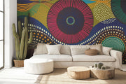 Vibrant abstract wall mural with bold geometric circular patterns, featuring bright colors and dynamic designs for modern interior decor. Styled in a living room with a sofa.