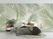 Serene palm leaf wall mural with soft green overlapping leaves on a neutral background, styled in a modern bedroom with wooden accents.
