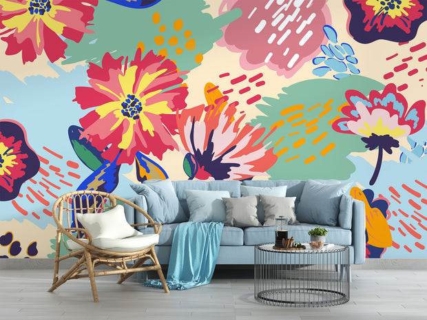 Vibrant floral wall mural with bold, hand-painted flowers in red, yellow, blue, and green, displayed in a modern living room setting.