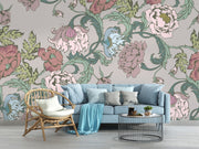 Garden bloom wall mural with pastel pink, green, and blue peonies and leaves, styled in a living room with light blue sofa and rattan chair.