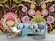 Opulent bloom wall mural with intricate lilac, peach, and green flowers on a dark background in a living room with blue sofa.