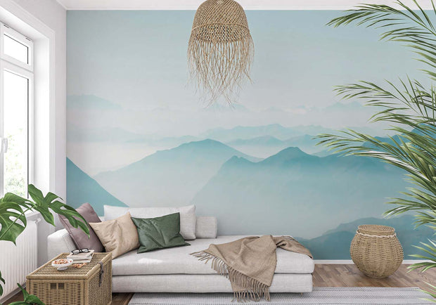 Serene misty mountain wall mural with soft blue gradient layers, creating a peaceful atmosphere in a modern living room setting.