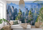 Zhangjiajie Mountain landscape wall mural featuring sandstone pillars, lush greenery, and misty peaks in a modern living room with natural decor.