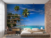 Palm oasis wall mural featuring tall palm trees, white sand, and turquoise waters under a bright blue sky, creating a refreshing workspace atmosphere.