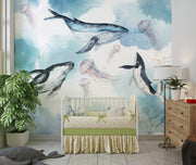 Underwater ocean wall mural with watercolor whales, jellyfish, and coral reefs in calming blue tones, displayed in a children's room with cozy decor.