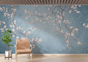 Cherry blossom wall mural with white flowers on twisting branches set against a rich blue background, creating a peaceful and stylish interior decor.