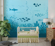 Underwater-themed wall mural featuring silhouettes of sharks, fish, and coral reefs in varying shades of blue, perfect for a calming and playful kids’ room.