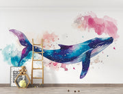 Vibrant galaxy whale wall mural featuring a watercolor-style blue whale swimming through a cosmic, star-filled background in shades of blue, purple, and pink – perfect for kids' rooms and modern decor.