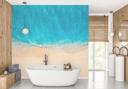 Crystal-clear ocean wave wall mural with turquoise waters and sandy shores, decorating a modern bathroom.