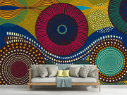 Vibrant abstract wall mural with bold geometric circular patterns, featuring bright colors and dynamic designs for modern interior decor. Styled in a living room ith a sofa.