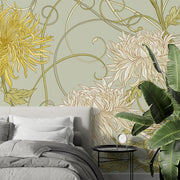 Art Nouveau floral wall mural with intricate yellow and beige chrysanthemum flowers on a sage-green background, styled in a modern bedroom.