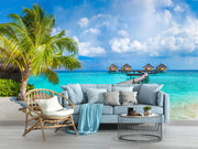 Tropical paradise wall mural with overwater bungalows, palm trees, turquoise sea, and a wooden pier, creating a serene and exotic room atmosphere.