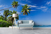 Palm oasis wall mural featuring tall palm trees, white sand, and turquoise waters under a bright blue sky, creating a refreshing workspace atmosphere.