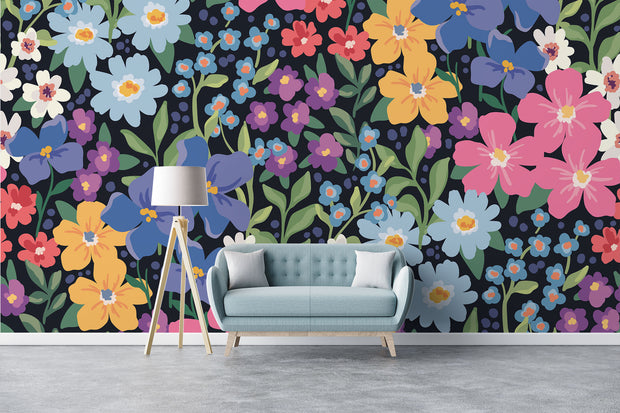 Colorful floral wall mural with hand-painted flowers in shades of blue, pink, yellow, and purple, displayed in a modern living room with a pastel sofa.