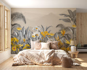 Modern tropical botanical wall mural with grayscale jungle leaves, vibrant yellow flowers, and a misty mountain backdrop in a cozy bedroom setting.