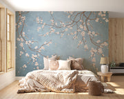Cherry blossom wall mural with white flowers on twisting branches set against a rich blue background, creating a peaceful and stylish interior decor.