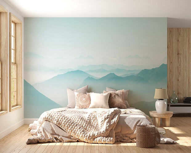 Serene misty mountain wall mural with soft blue gradient layers, creating a peaceful atmosphere in a modern bedroom setting.