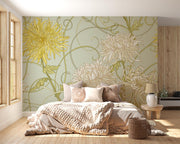 Art Nouveau floral wall mural with intricate yellow and beige chrysanthemum flowers on a sage-green background, styled in a cozy bedroom.