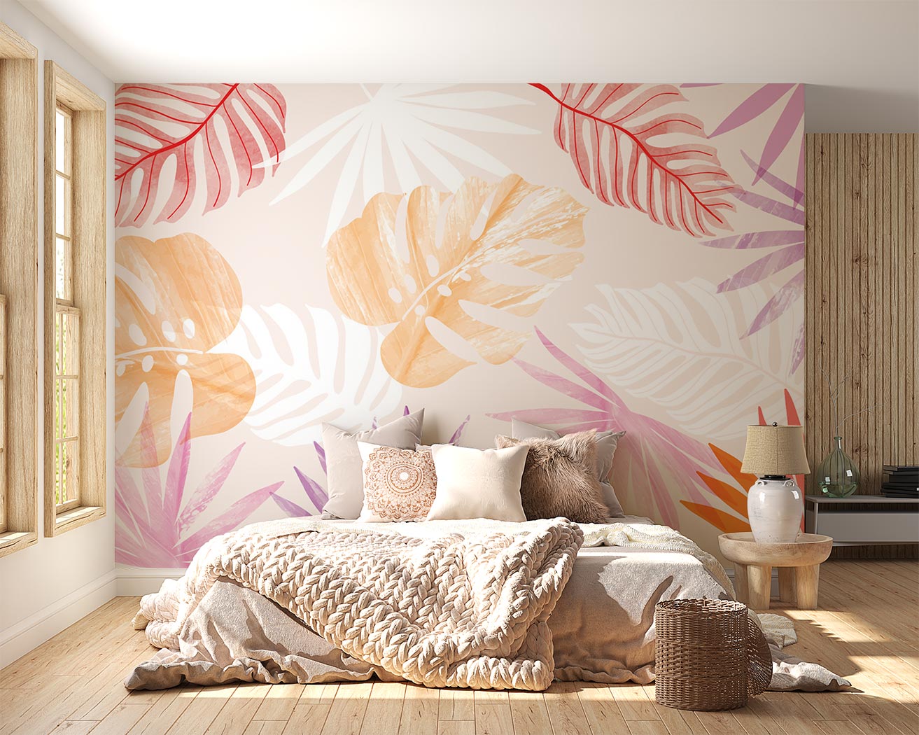 Colorful tropical leaf wall mural featuring overlapping monstera and palm leaves in soft orange, pink, and red tones, styled in a cozy bedroom.