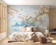 Chinoiserie-style wall mural featuring cherry blossom branches, perched birds, and misty blue mountains, creating a serene and elegant atmosphere.