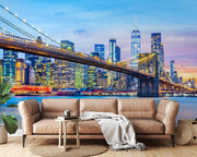 New York City Brooklyn Bridge wall mural featuring the Manhattan skyline at twilight in a modern living room with white decor.