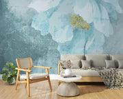 A modern living room with a Blue Floral Watercolor Wall Mural, featuring a delicate oversized flower in teal and gold hues. Creating a cosy and elegant space with a soft, artistic ambience.