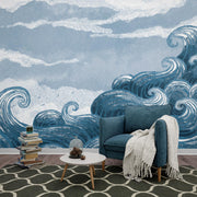 Wave themed wall mural with dynamic blue ocean waves and cloudy skies, decorating a modern living room.