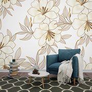Elegant gold floral wall mural with oversized flowers and intricate leaves, featured in a modern living room.