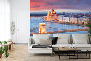 Budapest Skyline Wall Mural featuring the Hungarian Parliament, Chain Bridge, and the Danube River glowing under a vibrant sunset; decorating a living room.