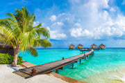Tropical paradise wall mural with overwater bungalows, palm trees, turquoise sea, and a wooden pier, creating a serene and exotic room atmosphere.