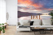 Wall mural of a sunset lake with a wooden dock extending into calm waters, adding warmth to a modern living room.
