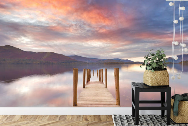 Wall mural of a sunset lake with a wooden dock extending into calm waters, adding warmth to a modern living room.