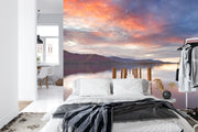 Wall mural of a sunset lake with a wooden dock extending into calm waters, adding warmth to a modern bedroom.