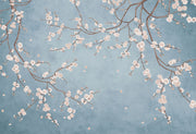 Cherry blossom wall mural with white flowers on twisting branches set against a rich blue background, creating a peaceful and stylish interior decor.