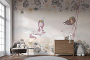 A whimsical nursery wall mural featuring a pink unicorn resting on clouds, a girl swinging with floral details, and soft pastel tones for a dreamy ambiance.