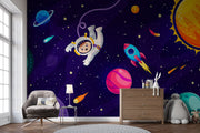 Cosmic explorer wall mural with cartoon astronaut, rocket ship, planets, and starry galaxy background in a playful kids’ bedroom.