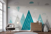 Modern geometric mountain wall mural in teal and grey with hot air balloons and clouds, styled in a contemporary nursery.