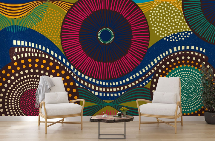 Vibrant abstract wall mural with bold geometric circular patterns, featuring bright colors and dynamic designs for modern interior decor. Styled in a living room with two chairs.