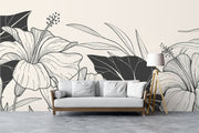 Modern living room with black and white floral wall mural featuring large line-art hibiscus flowers and bold leaves.