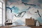 Underwater ocean wall mural with watercolor whales, jellyfish, and coral reefs in calming blue tones, displayed in a children's room with cozy decor.