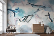 Underwater ocean wall mural with watercolor whales, jellyfish, and coral reefs in calming blue tones, displayed in a children's room with cozy decor.